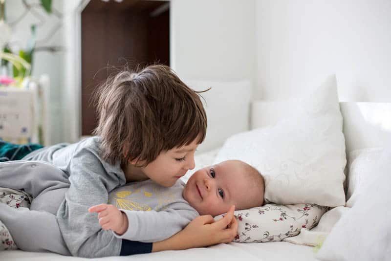 sweet little boy cuddling with his baby brother on the bed