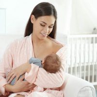 Young woman breastfeeding her baby in a nursery glider