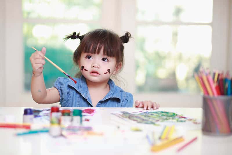 cute baby girl painting on the table