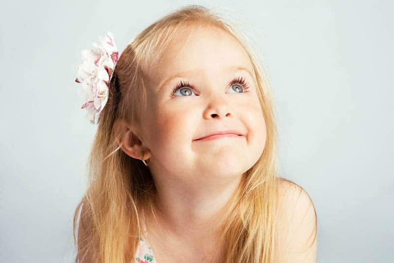 cute little girl with flower in her hair smiling and looking up