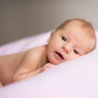 skinny baby laying on a white pillow