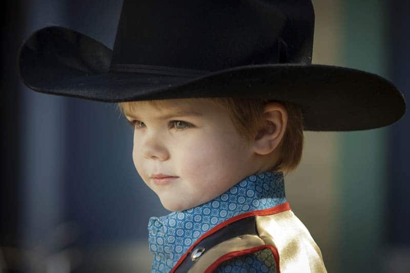 cute kid dressed like a cowboy standing outdoor