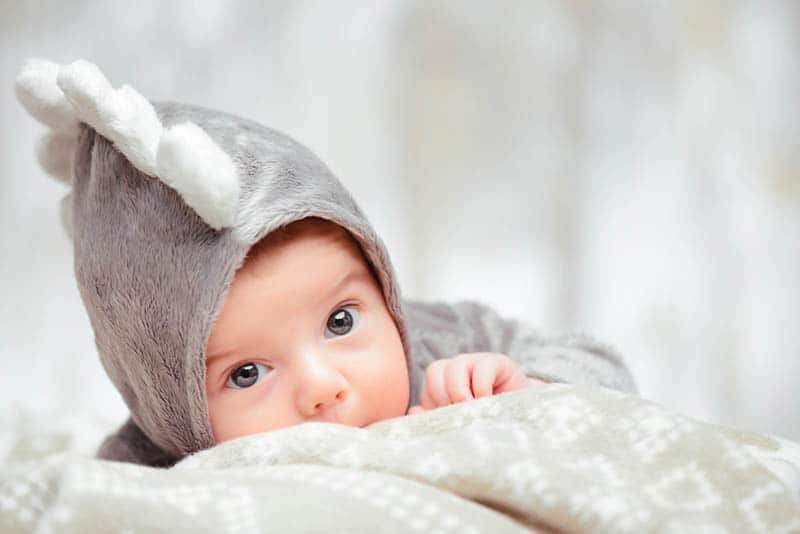 funny baby boy wearing baby costume while lying on the belly