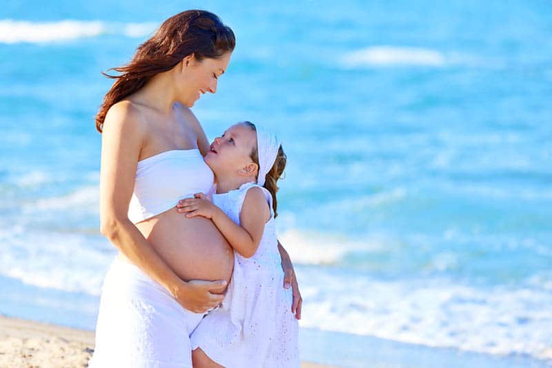 pregnant woman and daughter hugging on the beach