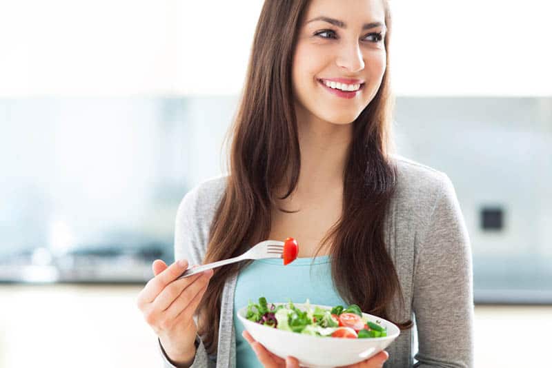 smiling young woman eating a salad