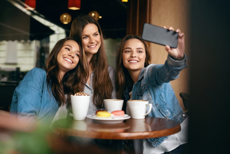 Schöne Freunde, die Fotos im Cafe machen