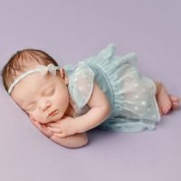 newborn baby sleeping on purple sheets