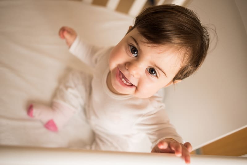Little cute baby smiling at camera in her cot