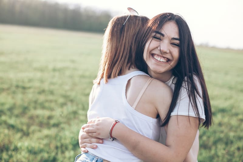 Due giovani donne che si abbracciano all'aperto