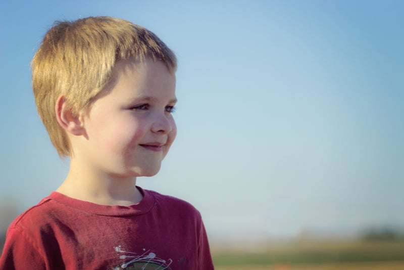 little blond boy smiling outdoors