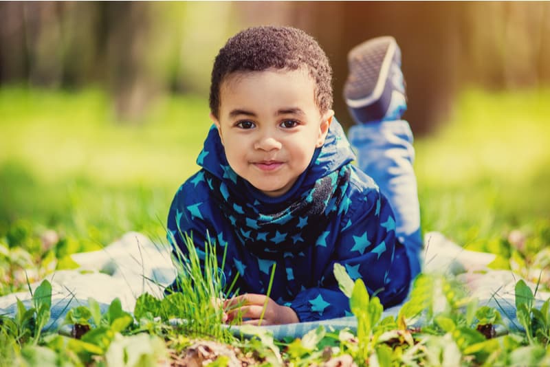  little boy lying in green grass on spring