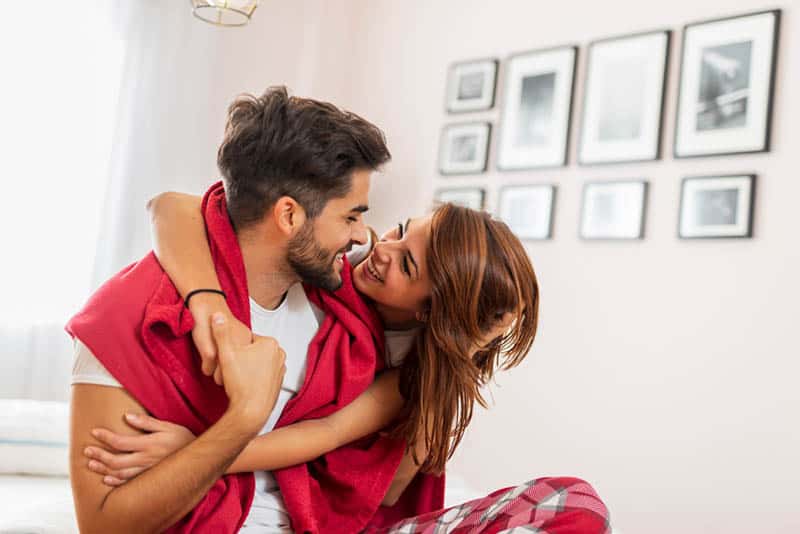 Couple in love cuddling and hugging in bed after waking up