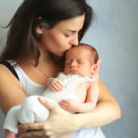 mother kissing her newborn baby boy