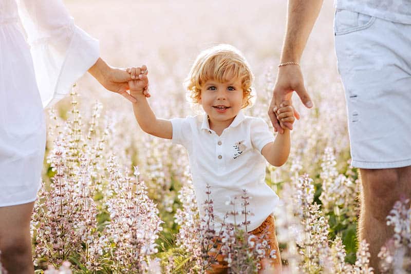happy little boy in meadow with parents
