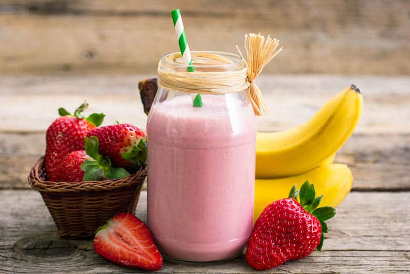 strawberry and banana smoothie in the jar with fresh strawberries and bananas
