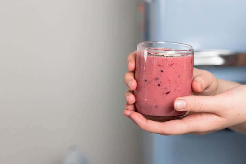 woman holding a glass of healthy smoothie made from fresh fruits