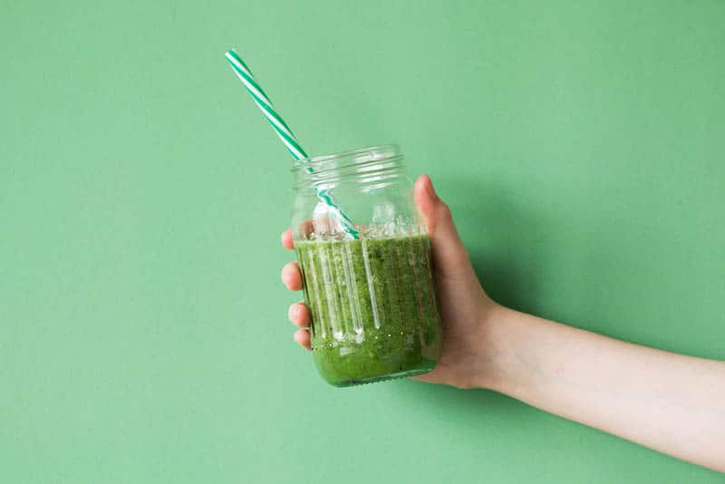 woman holding fresh smoothie made from greens