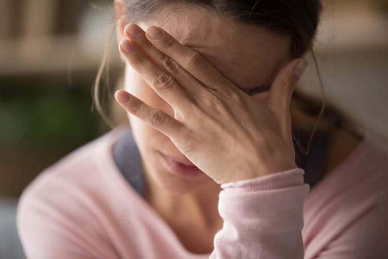  mujer preocupada sosteniendo una mano en la frente