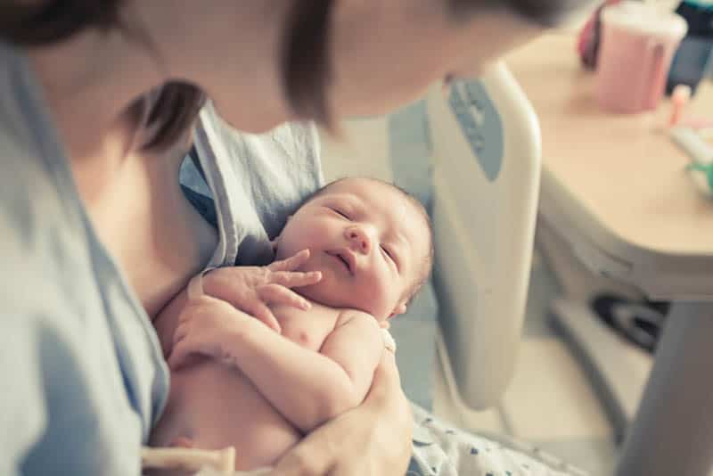 junge Mutter hält ein Neugeborenes in den Händen