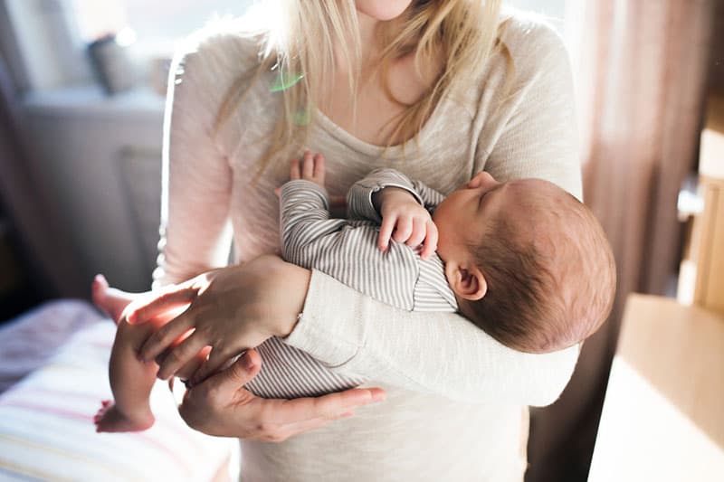 jovem mãe segurando seu bebê nos braços