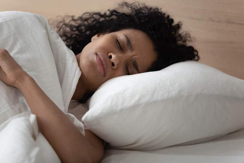 junge Frau, die einen Albtraum hat, während sie im Bett schläft