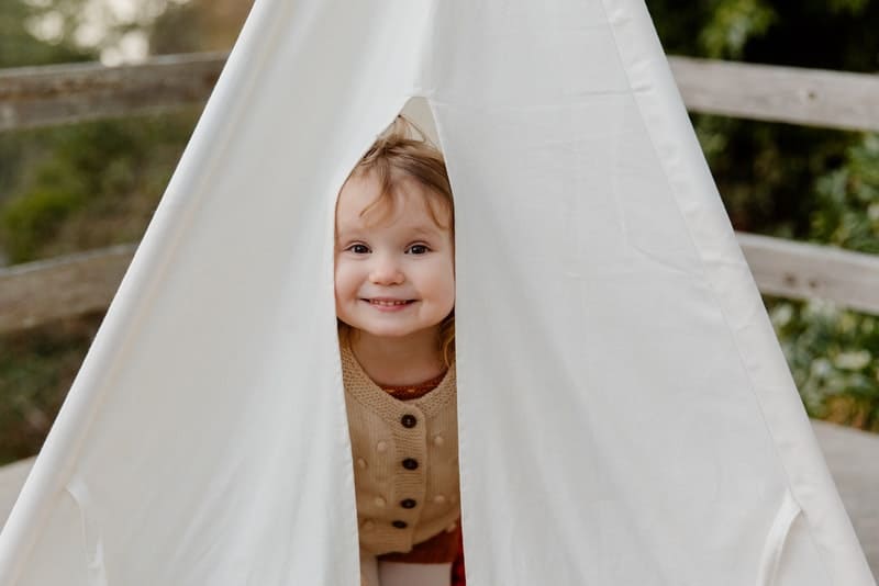 little girl peeking out of a tent