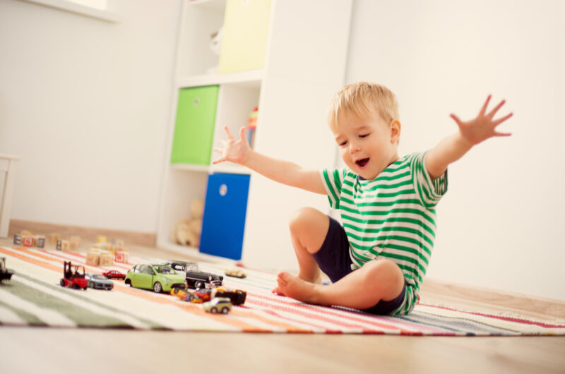 young boy playing with car toys